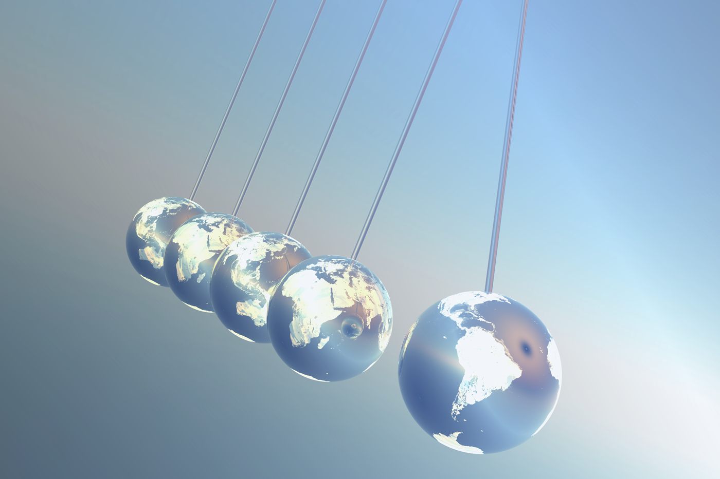 Small globes hung in a row like a desk pendulum, four swung back together and one held out on its own.